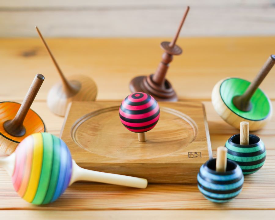 A collection of different Mader Spinning Tops and spinning plate on a table