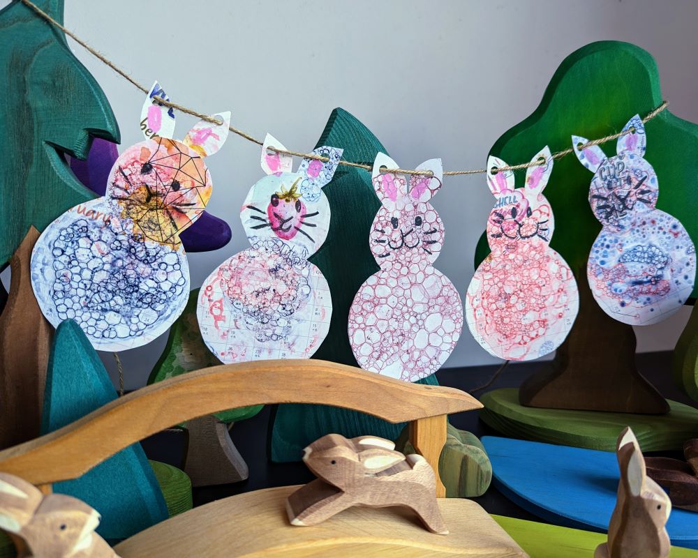 Bunny bunting hanging up over a Lunar New Year play scene with wooden rabbits, trees and a bridge