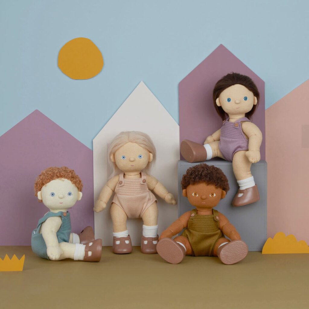 The four new Olli Ella dinkum dolls in different poses in front of a pastel wall