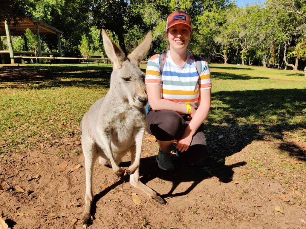 A person wearing a Patagonia cap sat next to a kangaroo