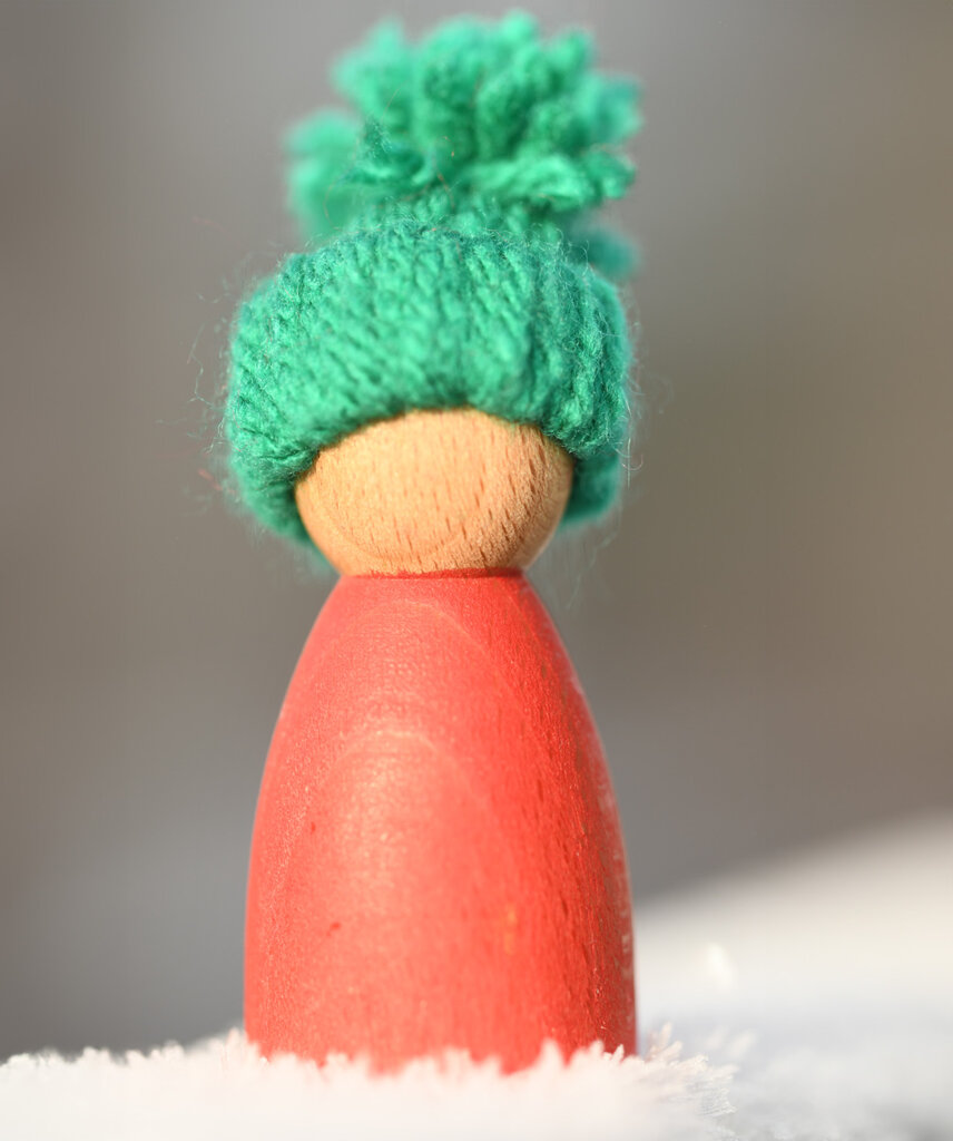 Orange peg doll wearing a DIY bobble hat